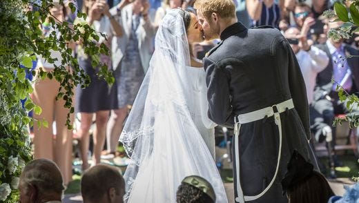 Prince Harry, Duke of Sussex kisses his wife Meghan, Duchess of Sussex as they leave from the West Door of St George's Chapel.