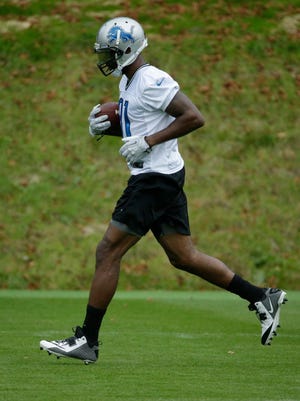 Detroit Lions wide receiver Calvin Johnson runs with a ball during a training session at Pennyhill Park Hotel in Bagshot, England, on Thursday, Oct. 23, 2014.