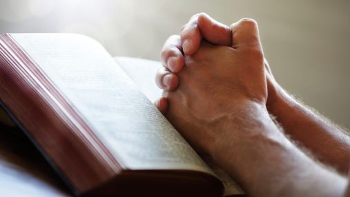 Praying hands on a Bible