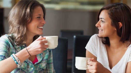 Two smiling students having a cup of coffee