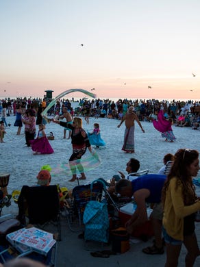 Seagulls fly over the community drum circle at Siesta Key Beach as the sun sets on the horizon on Sunday, January 21, 2018 in Sarasota. 