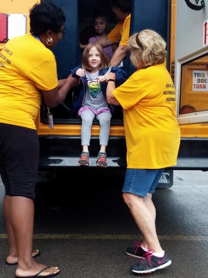 Maggie Corriveau is assisted by bus drivers Shawanda Flagler and Kathy Palmisano as she practices exiting the bus through the rear emergency door.