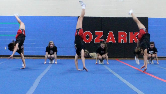 Ozark senior cheerleader Hallie Mayes (center) starts a tumbling pass during a practice Oct. 5 at Ozark Middle School.