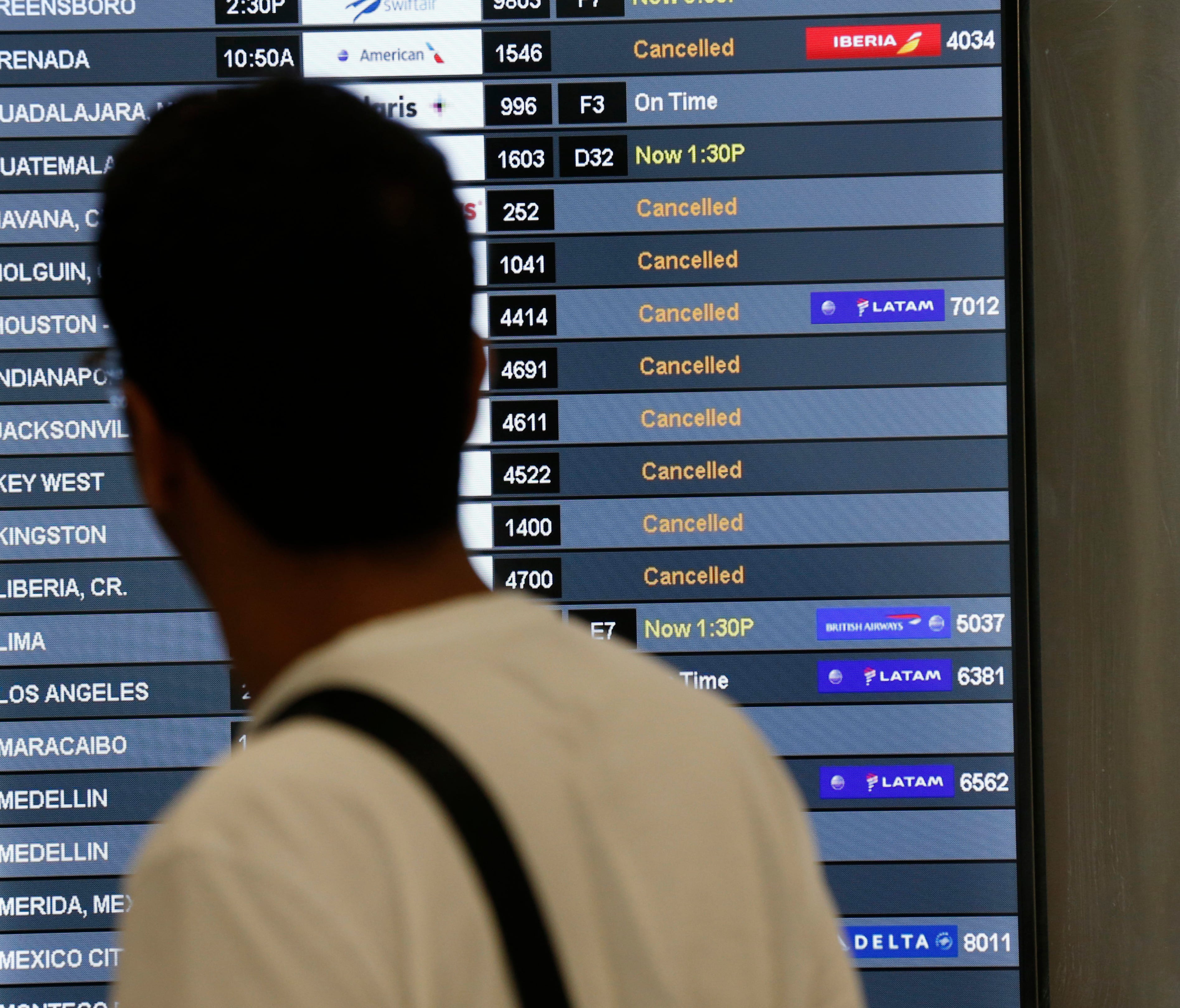 A traveler looks at a monitor listing canceled flights at Miami International Airport on Sept. 8, 2017.