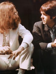John Lennon, left, and Paul McCartney talk during the