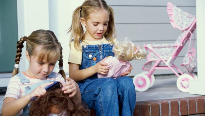 Two girls sitting together with their dolls