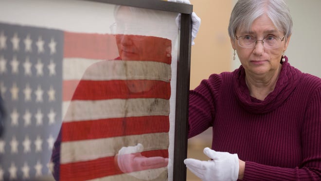 Alice Duckworth, collections manager of the Arizona State Capitol Museum, plans to re-unveil an oil-stained American flag that sunk with the ship at Pearl Harbor seven decades ago.