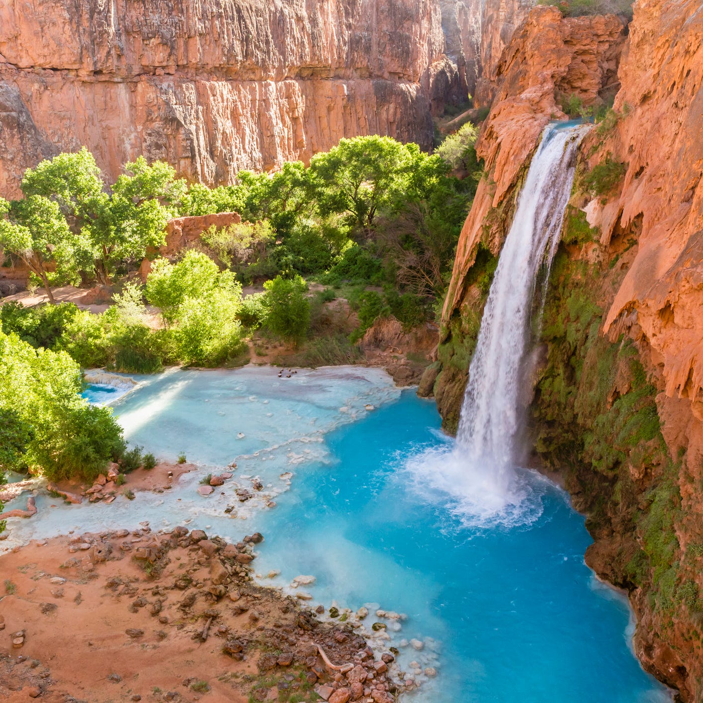 Hidden deep in the heart of the Grand Canyon, the bright blue waters of the creek spill over a cliff as Havasupai Falls, filling up a temptingly colored pool that entices swimmers to cool off in the desert heat.