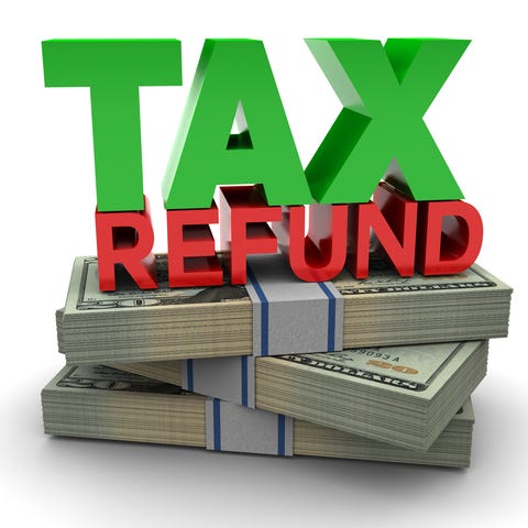 The words tax refund on top of three stacks of...
