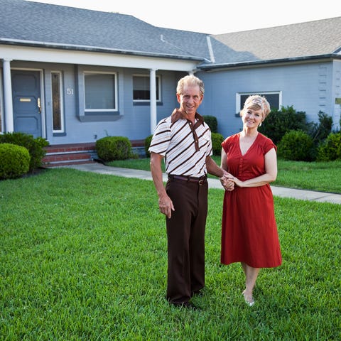 Senior couple standing on front lawn outside home