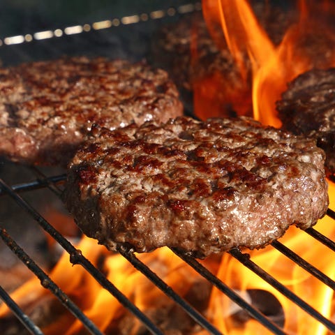 Several burger patties grilling over an open fire.