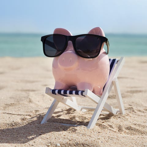 Piggy bank on the beach wearing sunglasses.