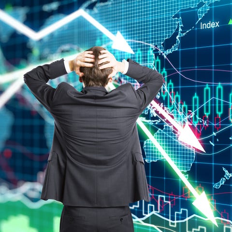 Man holding head in front of stock charts.