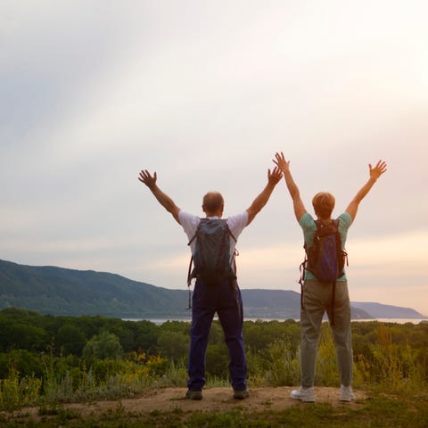 Two hikers standing at a vista with their arms out