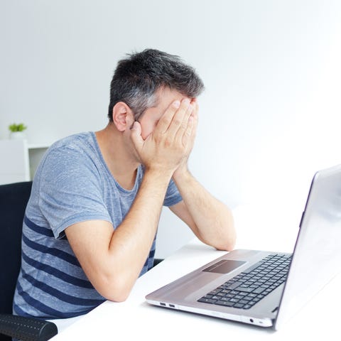 Man sitting at laptop, covering his face
