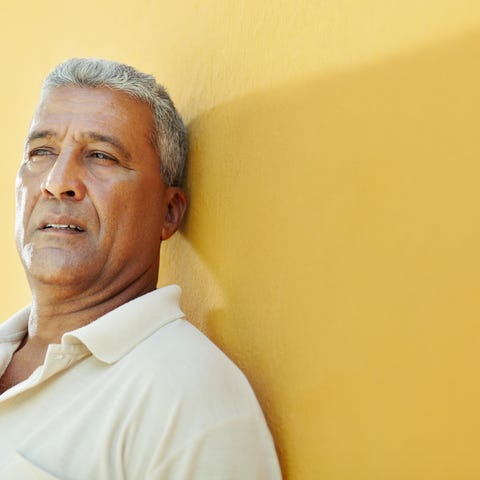 Older man with serious expression standing against
