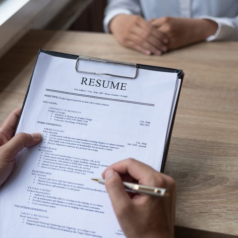 Person holding a pen to a resume on a clipboard wh