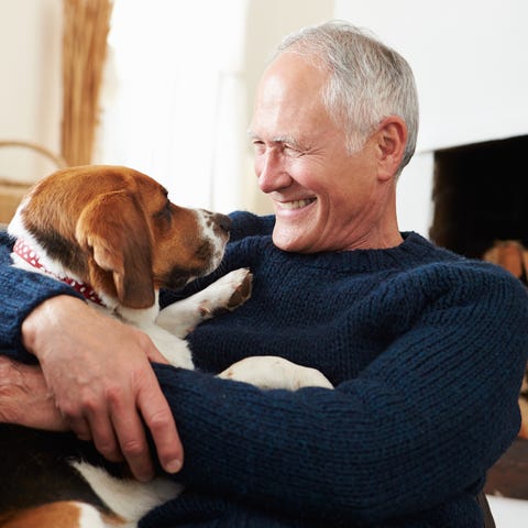 Older man smiling and holding dog