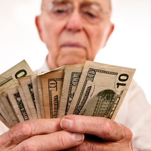 A senior man counting a fanned pile of cash in his