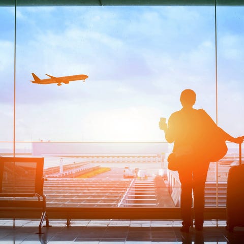 A woman stands in an airport while a plane takes o