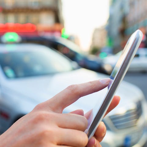 A person touching a smartphone's screen while a ca