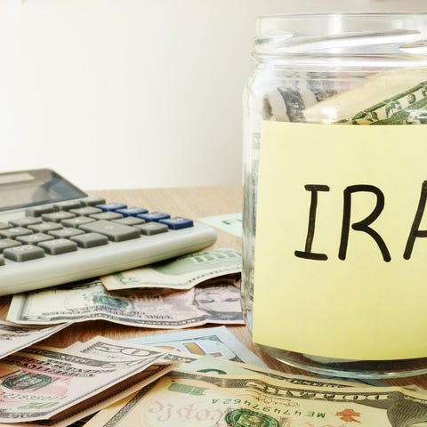 Money jar labeled IRA with cash on the desk around