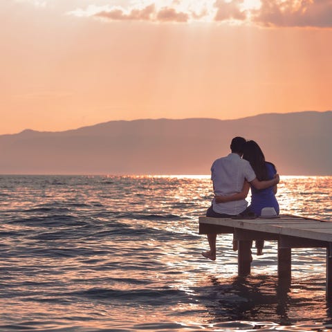 Couple sitting on a dock watching a sunset