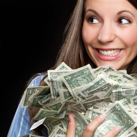 A smiling woman holding a pile of money
