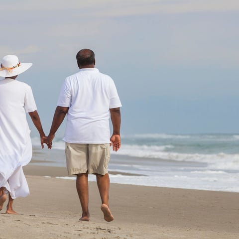 Two people holding hands walking on a beach.
