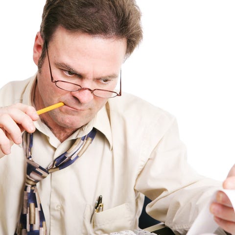 An accountant chewing on a pencil while closely ex