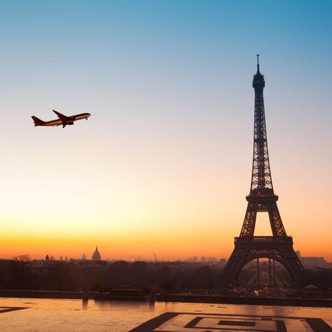 Airplane flying over Eiffel Tower at sunrise