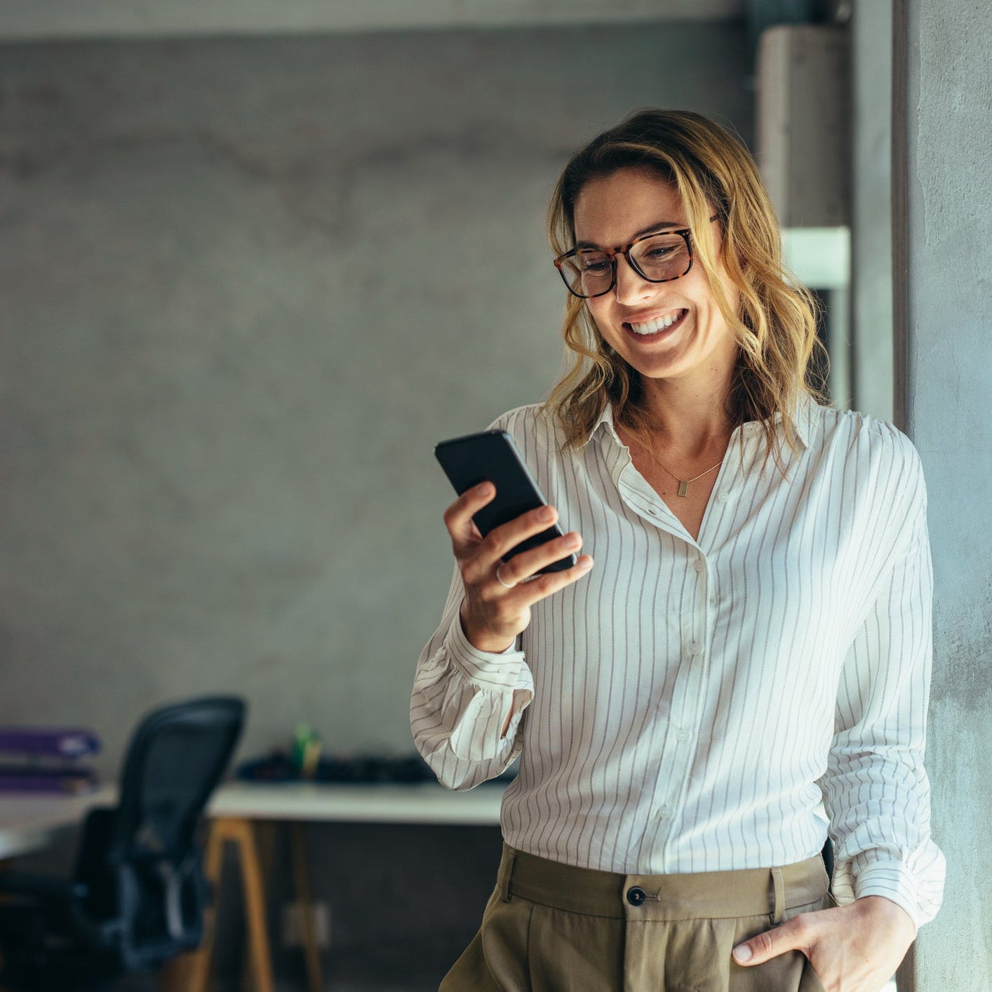 Woman smiling while looking at mobile phone in her hand