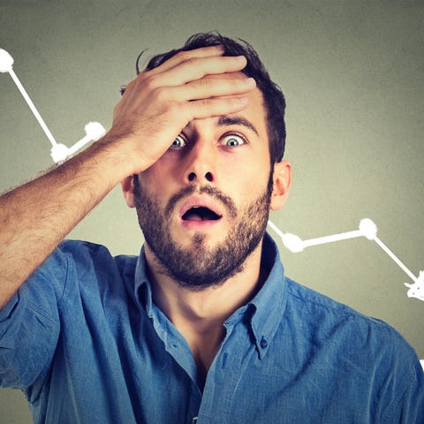 Man holding head in front of down stock chart