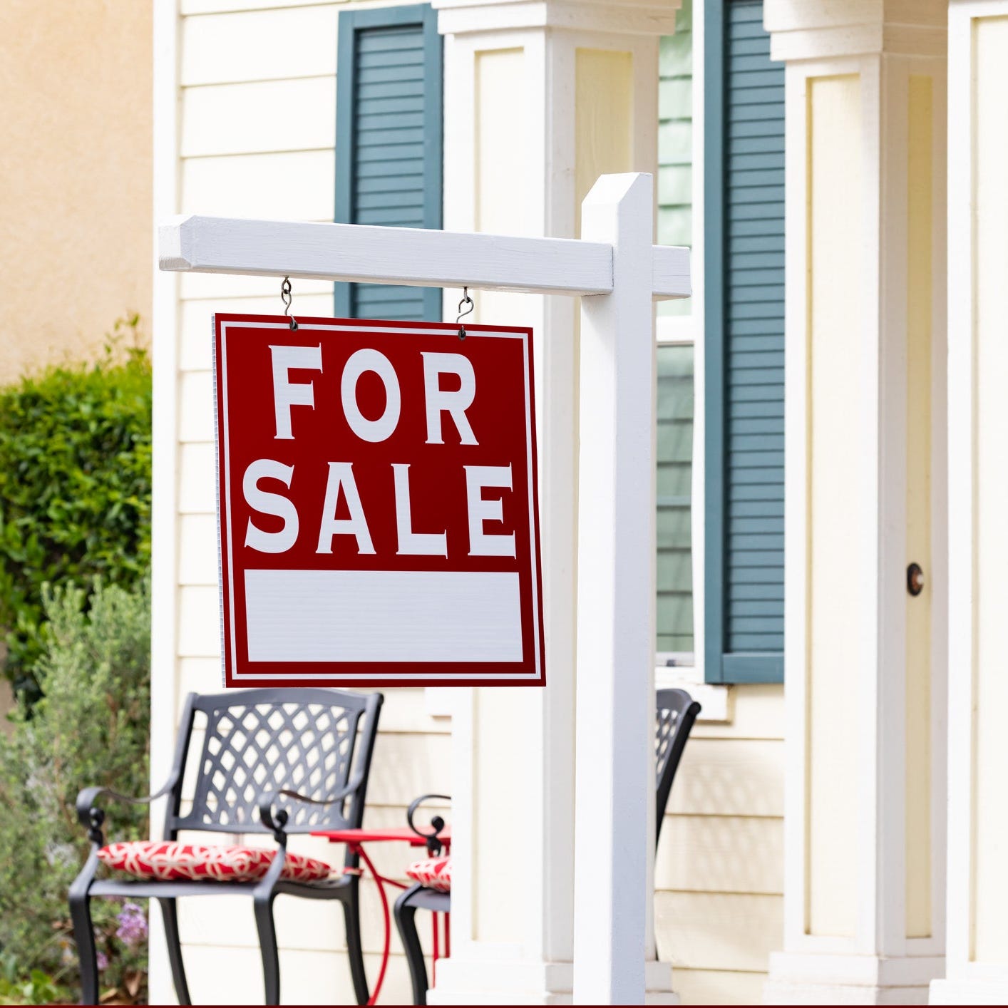 Front porch of home with for sale sign.