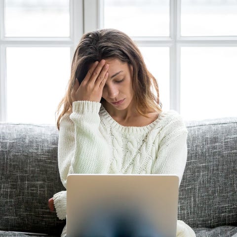 Woman looking at her laptop and holding her head i