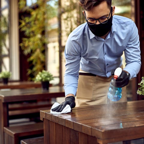 Man in mask and gloves sprays down table