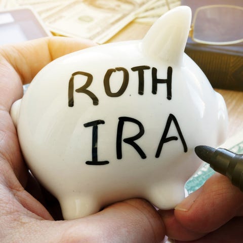 Hand holding piggy bank with Roth IRA written on i