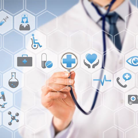 Doctor holding stethoscope up to a panel of health