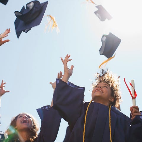 College graduates throw their mortarboards in the 