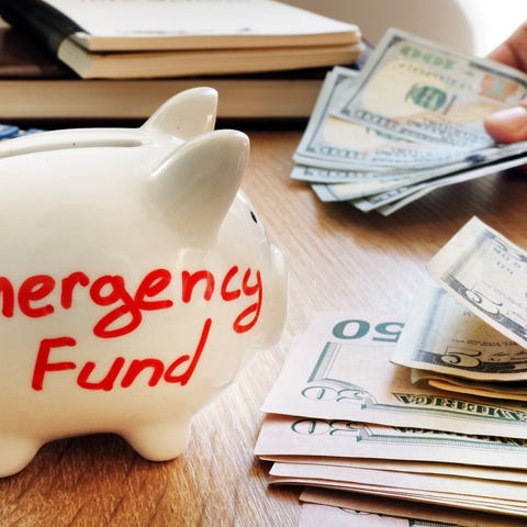 Emergency fund written on piggy bank with cash.