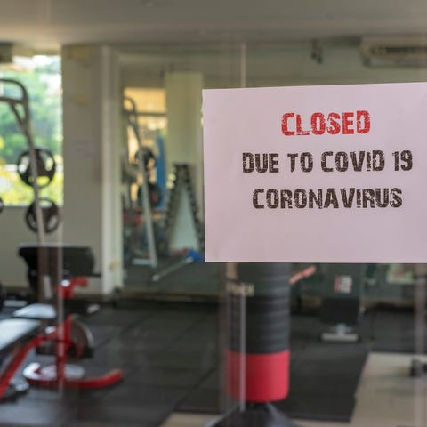 Glass gym wall with sign on it saying it's closed 