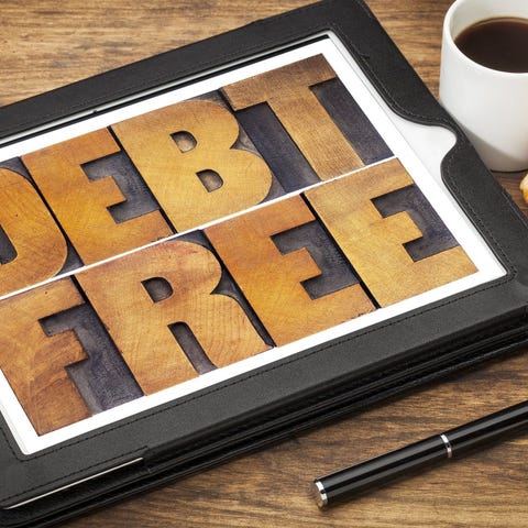 The words DEBT FREE carved into wood in a leather 