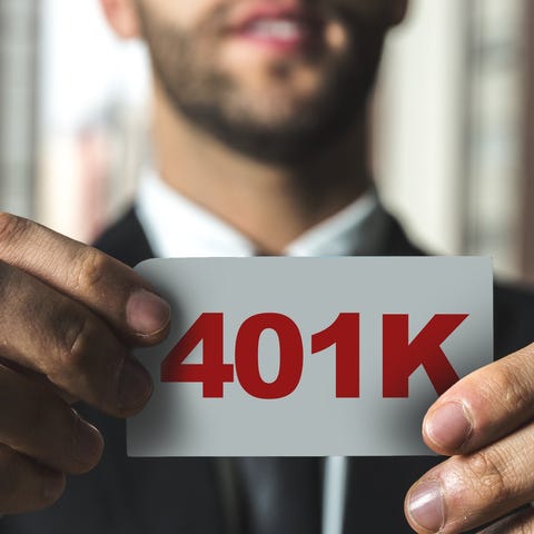Man holding up small white card with 401K on it in