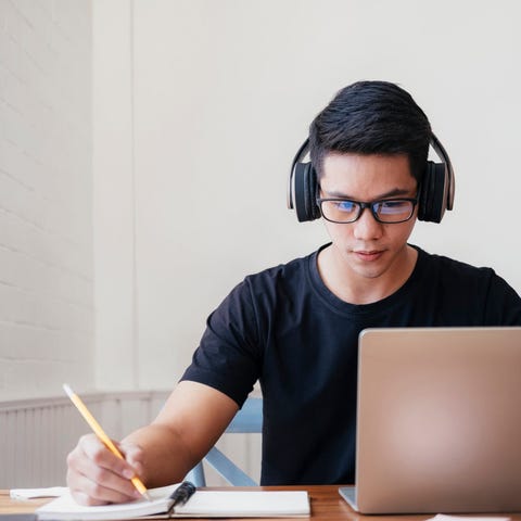 A young person wearing headphones works with a lap
