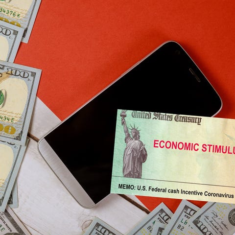 Economic stimulus check next to smartphone and $10