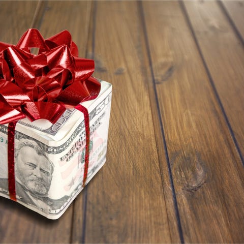 Christmas present with red bow wrapped in dollars.