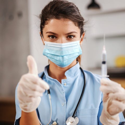 Healthcare worker wearing a mask giving a thumbs u