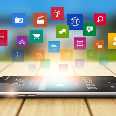 App icons floating above a smartphone lying on a w