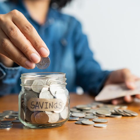 Woman putting coins in a jar labeled Savings