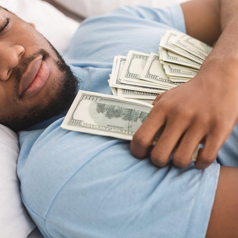 A man is sleeping, clutching hundred-dollar bills.